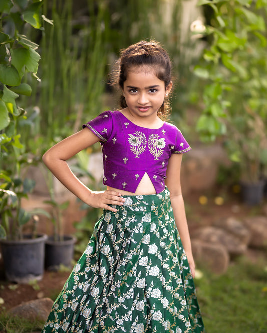 A DARK GREEN JAAL BANARASI LEHENGA WITH PURPLE RAW SILK BLOUSE.